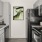 a kitchen with white cabinets, black appliances and painting on the wall